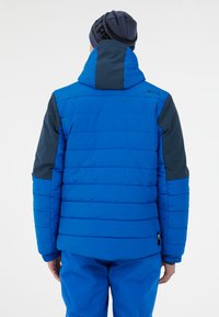 Modrá prošívaná bunda s kapucí, s horizontálním prošíváním, tmavší modré akcenty na rukávech a elastickými manžetami. Lehký materiál.