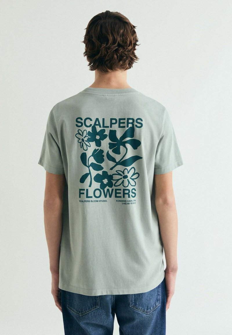 Grøn bomuld t-shirt med blomsterprint og teksten "SCALPERS FLOWERS" på ryggen. Kortærmet og med afslappet pasform.