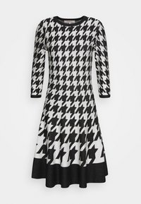 Czarna i biała sukienka dzianinowa w wzór houndstooth z trzema ćwiartkami rękawów, okrągłym dekoltem i rozkloszowanym dołem. Teksturowany materiał z obszytym brzegiem.