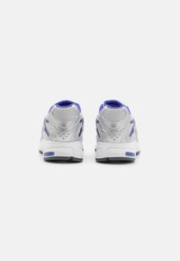 Hopeiset urheilukengät, joissa on purppuran sävyjä, verkkokankaita ja pehmustettu kaulus. Erityiset tekstuurilla varustettu takapää ja tukevan muotoilu.