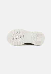 Die Schuhsohle weist eine gewellte Textur auf, mit kreisförmigem Griff und Belüftungsöffnungen, überwiegend in Weiß mit dezentem Branding.