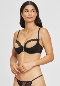 Zwarte lingerieset met een rand van paardenbloemkant, doorschijnende cups en decoratieve zilveren accenten. Glad materiaal met dunne, verstelbare bandjes.