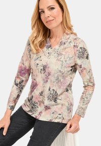 Blumenoberteil mit langen Ärmeln und V-Ausschnitt, aus weichem Stoff in Rosa-, Lila- und Schwarztönen, das verschiedene Blumenmuster zeigt.