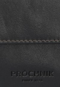 Czarny skórzany portfel o teksturowanej powierzchni, ze szwami i wytłoczonym logo "PRÓCHNIK SINCE 1948" na dole.