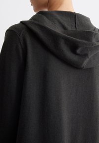 Dark gray hoodie with a soft texture, featuring a contoured hood, clean lines, and a relaxed fit, showcasing simplicity in design.