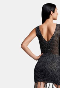 Vestito nero in maglia con scollatura a V profonda e silhouette aderente. Presenta bordi frangiati all'orlo, che aggiungono texture al design.