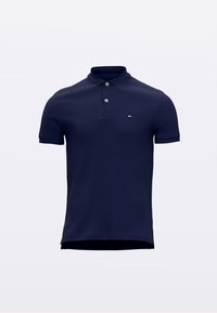 Marineblå polo skjorte laget av bomullsblanding, med klassisk krage, tre knapper og en liten logo på venstre bryst. Korte ermer.