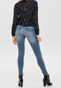 Smala jeans i blekt blå denim, med en slät yta och minimal blekning. I kombination med svarta klackade ankelstövlar.