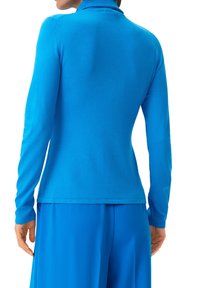 Sweter z długim rękawem w intensywnym niebieskim kolorze, gładka faktura, dopasowany krój, z wysokim kołnierzem i prostym dołem, noszony z pasującymi spodniami.