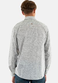 Lange mouw blouse in lichtgrijs met een geometrisch patroon, voorzien van knoopmanchetten en een klein logodetail op de achterkant.