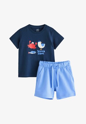 Tummansininen taaperoiden t-paita, jossa rapu-, lokki- ja kala-aiheiset kuvat sekä teksti "Skipper School", yhdistetty vaaleansinisiin, joustavaan vyötäröön ommeltuihin shortseihin.