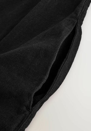 Zwart textiel met een zachte, licht gestructureerde oppervlakte, voorzien van een geplooide rand en een nette naad. Geen extra patronen of hardware zichtbaar.