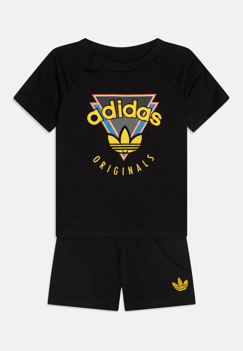 Svart bomull tvådelad set med en kortärmad skjorta som har en gul Adidas-logotyp och ett grafiskt mönster, i kombination med matchande shorts.