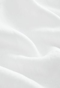 Tissu blanc lisse avec des plis doux et une texture subtile, éclairé uniformément sans motifs ou objets visibles.