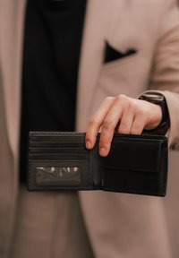 Black leather wallet held open, featuring card slots, a transparent ID window, and a small pocket. Smooth texture and minimalist design.