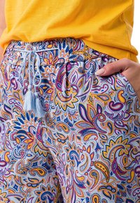Pantalons légers à motifs avec un design paisley bleu et blanc, dotés d'une taille élastique à cordon de serrage et de poches latérales. Texture douce.
