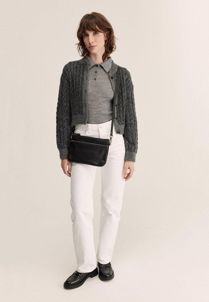 Gray knitted cropped cardigan, gray polo shirt, white straight-leg jeans, black crossbody bag, and black lace-up shoes.
