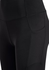 Höga svarta leggings gjorda av slät, elastisk tyg med platta sömmar och en sidficka för förvaring.