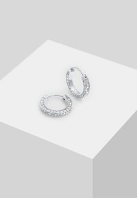 Orecchini a cerchio in argento con cristalli trasparenti lungo il bordo esterno. Design arrotondato con chiusura a cerniera, superficie metallica liscia e finitura lucida.