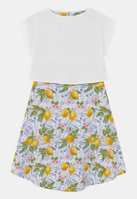 Valkoinen lyhyt toppi, joka on yhdistetty kellotettu hame, jossa on sininen kukkakuosi, jossa on keltaisia sitruunoita ja vaaleanpunaisia kukkia. Puuvillakangasta, rento muotoilu.