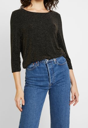 Zwarte, sprankelende top met lange mouwen en een brede halslijn, gecombineerd met high-waisted blauwe jeans. De stof heeft een zachte textuur en een subtiele glans.