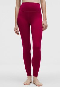 Fukszia színű, magas derekú leggings rugalmas anyagból, sima textúrával és testhezálló kialakítással, amely a bokáig ér.