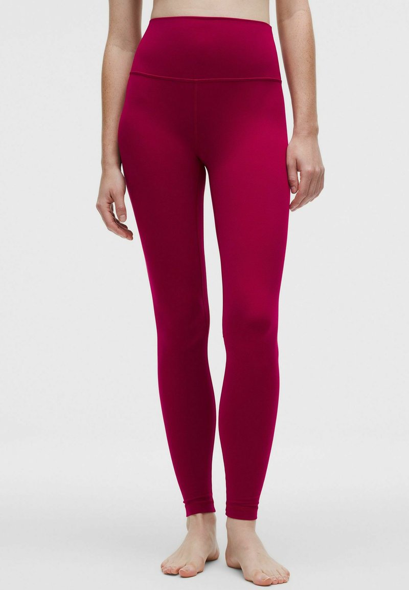 Fukszia színű, magas derekú leggings rugalmas anyagból, sima textúrával és testhezálló kialakítással, amely a bokáig ér.