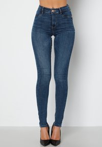Džínsy s vysokým pasem v tmavě modrém denimovém provedení s mírným vyblednutím, pět kapsami a předním zapínáním na knoflík. Hladká textura se švy jako akcenty.