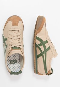 Beige læder sneakers med grønne detaljer og tekstureret ruskind. Har hvide striber, snørebånd og en mønstret indersål. Gummiydersål.