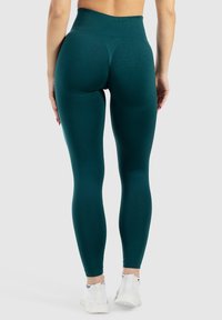 Legginsy z wysokim stanem w głębokim odcieniu teal, wykonane z elastycznego, teksturowanego materiału. Posiadają szczegóły szwów z tyłu oraz długość do kostek.