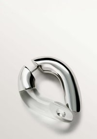 Diseño de hebilla de metal plata y plástico transparente con una forma suave y curvada. Presenta un acento de joya clara en la sección de plástico.