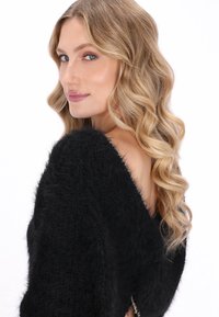 Zwarte, donsachtige trui met een off-shoulder ontwerp, voorzien van een zachte textuur en een subtiele glans, met een zijdetail met hardwareaccent.