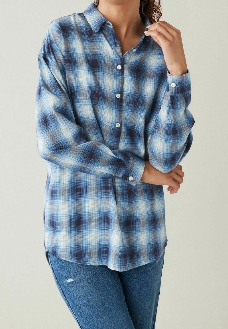 Camicia a quadri blu e navy con vestibilità rilassata, maniche lunghe e colletto classico; realizzata in un tessuto morbido e leggero.