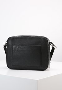 Borsa a tracolla nera in pelle con superficie texturizzata, forma rettangolare, hardware in tonalità argentata e un dettaglio con tasca posteriore.