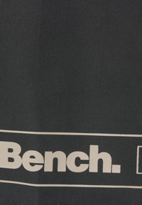 Crna tkanina s velikim bijelim otisnutim logom "Bench." ispod koje se nalazi horizontalna bijela pruga, koja naglašava naziv branda.