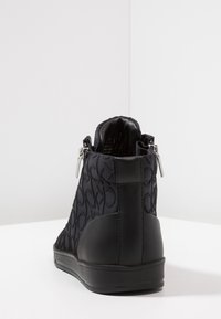 Černé kotníkové boty s textilním svrškem, který má jemný vzor loga, kožené detaily a boční zipy pro snadné obutí. Plochá podešev.