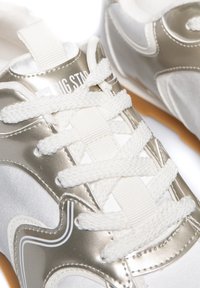 Białe i metaliczne srebrne sneakersy z teksturowanej tkaniny, płaskimi białymi sznurówkami, gumową podeszwą oraz logo nadrukowanym na języku.