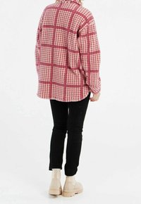 Vaaleanpunavalkoruudullinen flanellipaita pitkillä hihoilla, yhdistetty mustiin kapealahkeisiin housuihin ja beigenvärisiin nilkkureihin. Pehmeä materiaali, rento istuvuus.