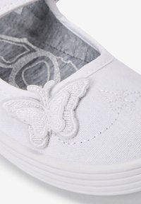 Weißer Stoffschuh mit abgerundeter Zehenpartie und weißen gestickten Schmetterlingsdetails. Graues gemustertes Innenfutter, Gummisohle mit leicht erhöhter Kante.