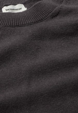 Grijze gebreide trui met een geribbelde ronde hals en een zachte textuur, voorzien van een wit label met de merknaam aan de binnenkant van de kraag.