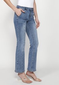 Ljust blå denimjeans med rak benpassform, femficksdesign och subtila blekningar. Har en standard midja och dragkedjestängning.