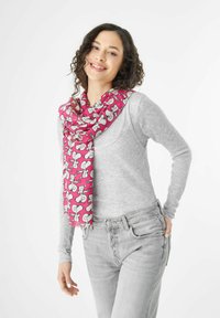 Écharpe rose avec imprimé de chien en cartoon, en tissu léger, drapée de façon décontractée autour du cou. Portée sur un haut à manches longues gris et un jean.