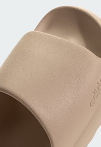 Tan slide sandal med en strukturerad yta och slät finish; design med öppen tå, något avsmalnande form, med präglad logotypdetalj.