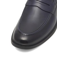 Námornícky kožený mokasín s hladkým povrchom, zaoblenou špičkou a ozdobným pásom cez prednú časť. Obsahuje prešívanie pozdĺž okrajov.