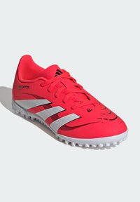 Scarpe da calcio di colore rosa brillante realizzate in materiale sintetico. Presentano dettagli neri e tre strisce bianche. Parte superiore testurizzata e suola in gomma sagomata.