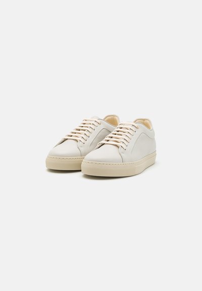 Zapatillas de cuero blancas con cordones color crema. Punta redonda, bajo perfil, paneles laterales texturizados y suela de goma crema. Diseño minimalista.