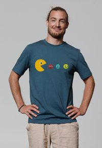 Blauwe katoenen t-shirt met een gele Pac-Man graphic en vier gekleurde spookfiguren in een speels ontwerp. Korte mouwen en ronde hals.