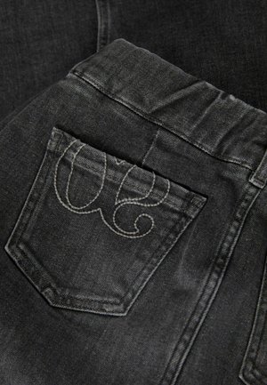Schwarze Jeans aus Denim mit strukturierter Oberfläche, ausgestattet mit einer Gesäßtasche, die mit grauem Gestick in einem spiralförmigen Design verziert ist.