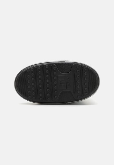 Semelle de chaussure en caoutchouc noir avec une surface texturée, présentant des motifs de grip circulaires et linéaires. Matériau durable avec un bord lisse.