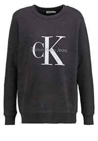 Felpa nera in cotone con colletto rotondo, polsini a costine e un grande logo bianco con la scritta "Calvin Klein Jeans" sotto.
